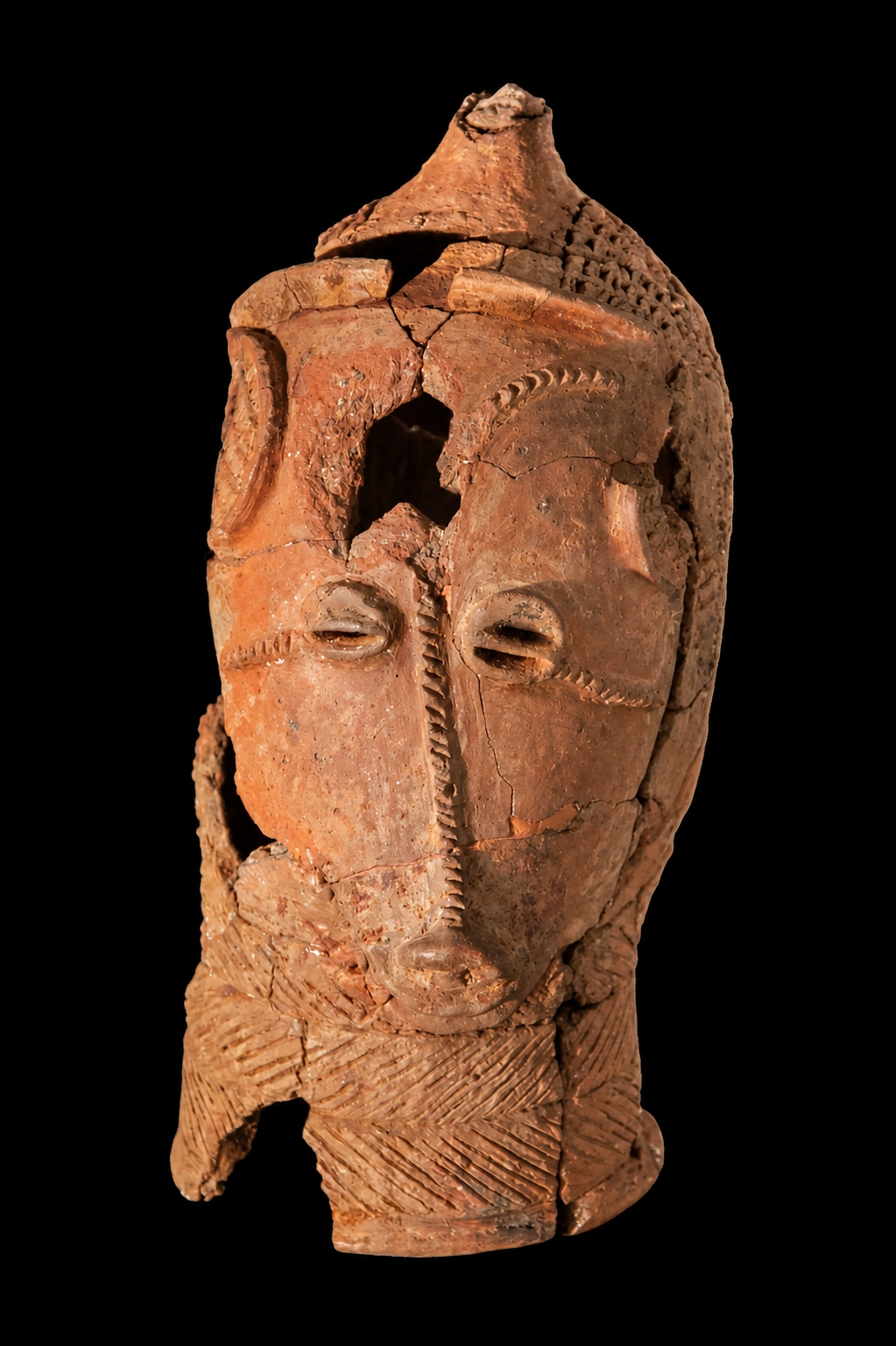 Recreación interpretativa de una cabeza fragmentaria de terracota del conjunto de siete de Lydenburg, basada en una fotografía de Mike Peel; ejemplar zoomorfo aislado sobre fondo negro, con sus lagunas conservadas.