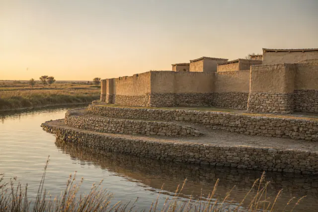 Reconstituição interpretativa de Els Vilars durante o século IV a. C.: fosso inundável e muralha de pedra e adobe, com alçados hipotéticos.